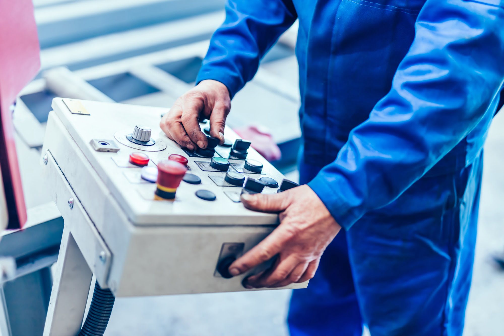 Worker operating saw machine for cutting steel profiles in a factory