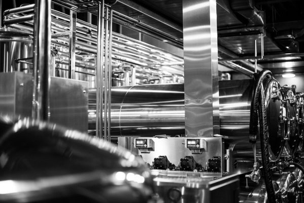 Black and white photo of modern brewery equipment with pipes and fermenting tanks